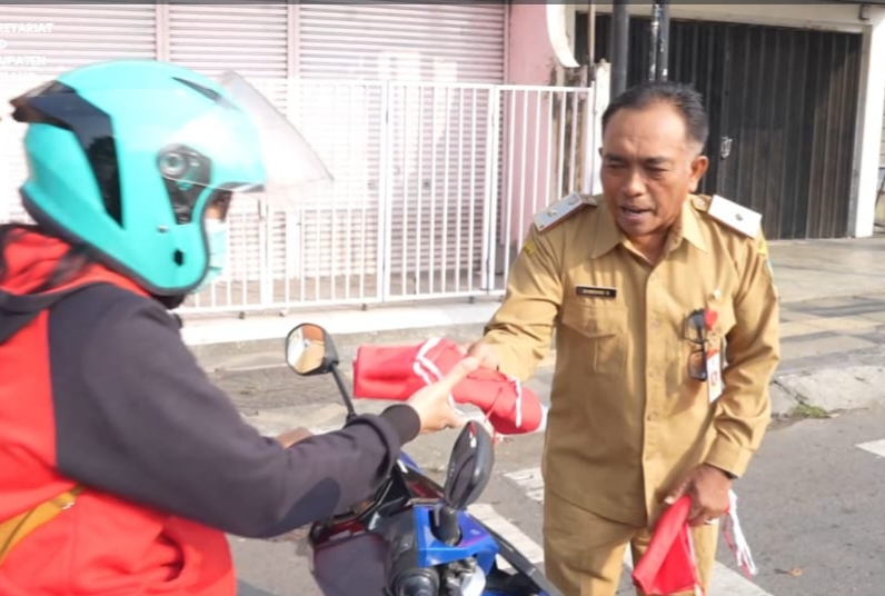 REFLEKSI HUT RI: Sekretaris DPRD Kabupaten Jombang, Bambang Sriyadi membagikan bendera merah putih kepada para pengguna jalan di depan Kantor DPRD. FOTO MITRAMEDIA