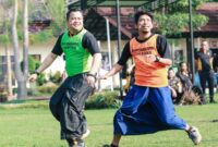 Kapolres Jombang, AKBP Ardi Kurniawan (kiri) mengenakan sarung saat berebut bola dengan jurnalis Fredi Prasetyo atau Gus Fredi di Lapangan Mapolres Jombang. DOK MITRAMEDIA