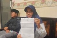 Korban saat menunjukkan bukti laporan polisi. (MITRAMEDIA)